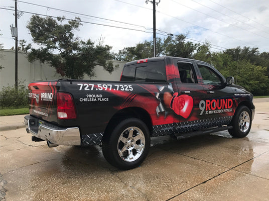 Black pickup truck with red and white graphics and text on a concrete surface.
