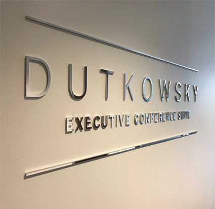Metal dimensional sign with 'DUTKOWSKY EXECUTIVE CONFERENCE SUITE' on a neutral background