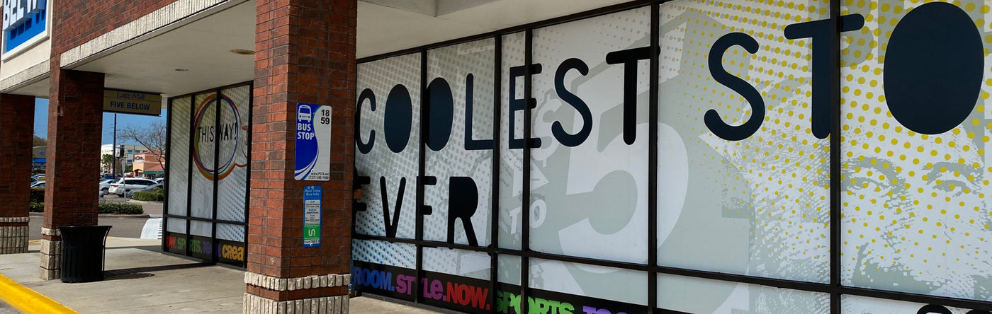 Window graphic on a storefront glass wall with text 'COOLEST STORE EVER' and colorful design elements.