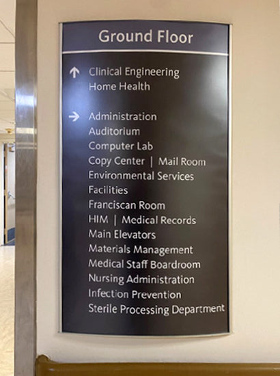 Directional sign in Vista frame on a wall indicating various locations on a hospital ground floor.