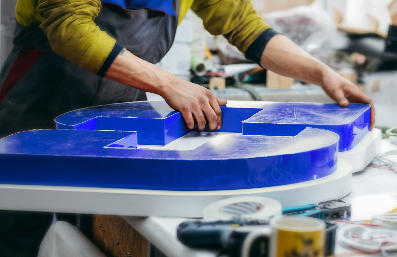 Closeup of a man's hands constructing an illuminated sign.