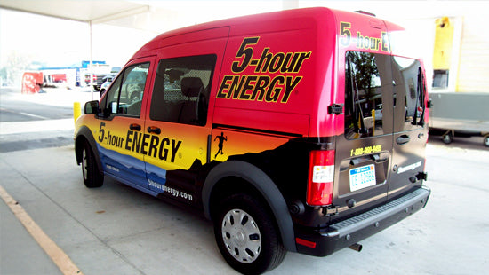 Van with colorful 5-hour ENERGY vehicle wrap parked at a gas station