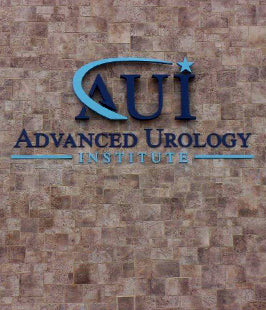 AUI Advanced Urology Institute dimensional letters and logo on a brick wall background
