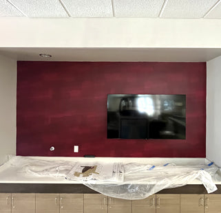 TV mounted on a wall with red wallpaper in an office setting