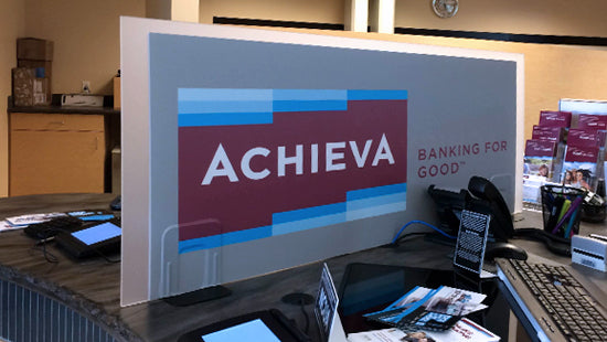 Achieva logo on a cubicle divider screen in an office setting