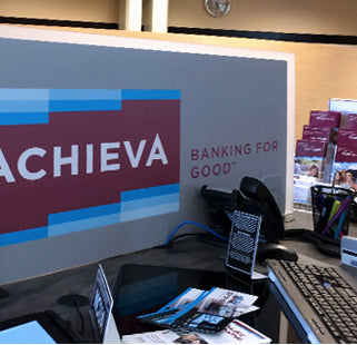 Branded cubicle divider with Achieva logo and 'Banking for good' text