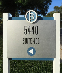 Outdoor post and panel  sign with address '5440 Suite 400' and a logo on a grassy background