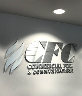 Metallic logo and letters of CFC Commercial Fire & Communications on a wall.