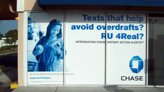 Chase bank advertisement on a storefront window graphic with a woman using a phone.