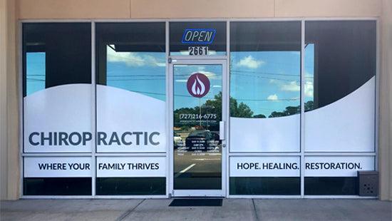 Front of a chiropractic clinic with large glass windows and branding on window graphic.