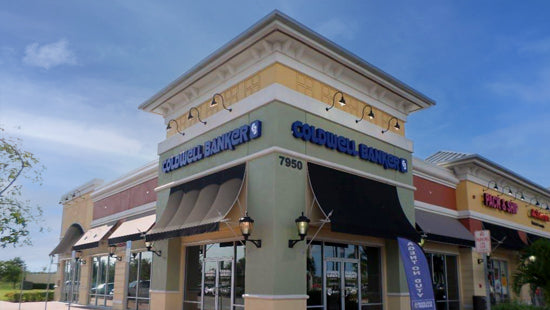 Coldwell Banker blue illuminated channel letters on exterior of commercial building against a blue sky
