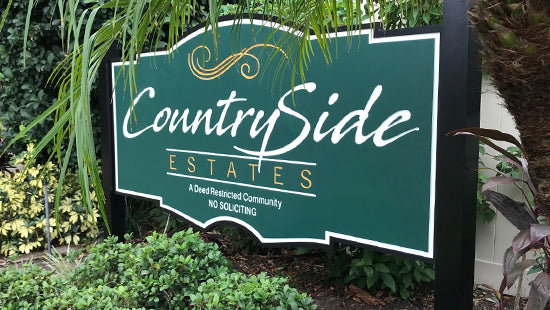 Green post and panel sign with 'Countryside Estates' text in a garden setting