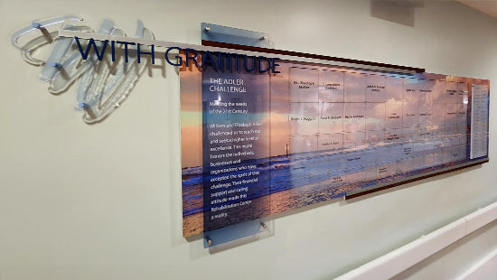 Dimensional Acrylic wall display with text 'WITH GRATITUDE' and a scenic design on a white wall.