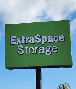 Green temporary sign banner with 'ExtraSpace Storage' text against a blue sky