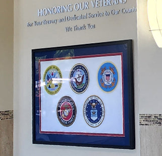 Framed print of military seals below dimensional lettering that reads' Honoring our Veterans.'