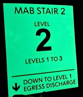 Illuminated wayfinding sign with text indicating MAB Stair 2 levels and egress discharge directions.