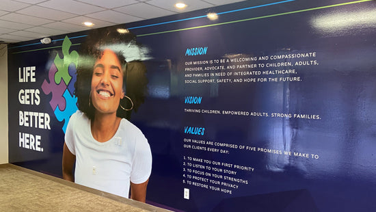 Wall mural with a woman's face and mission, vision, values text on a blue background