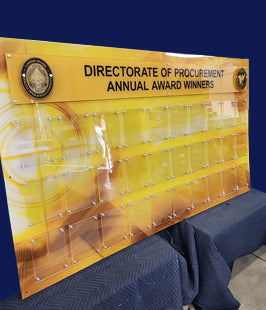 Acrylic display stand with 'Directorate of Procurement Annual Award Winners' text and logo.