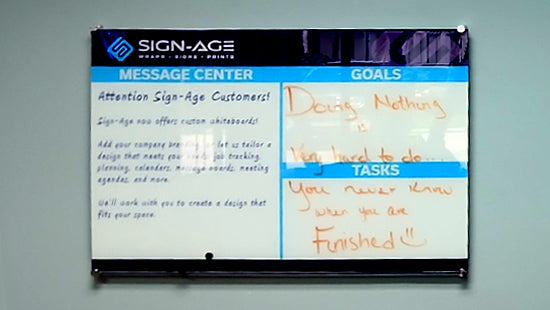 Custom whiteboard design on an office wall, with printed text and handwritten messages.
