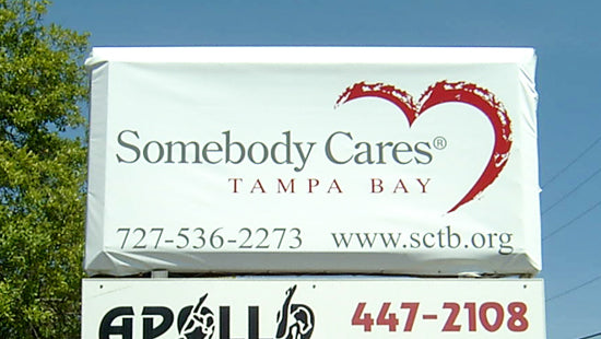 Temporary sign for 'Somebody Cares Tampa Bay' with contact information and Apollo logo.