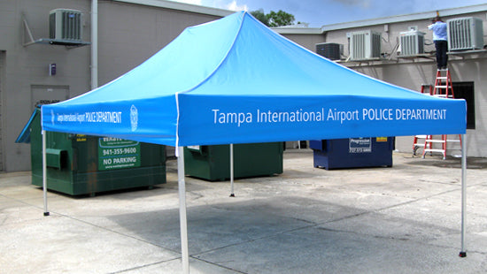 Blue canopy tent with 'Tampa International Airport Police Department' branding in an outdoor setting.