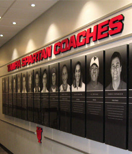 Recognition plaques on a wall with lettering above that reads 'Tampa Spartan Coahes'
