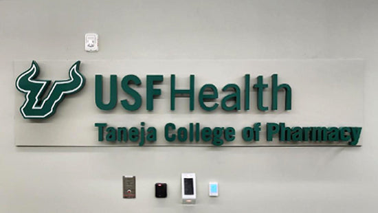 USF Health Taneja College of Pharmacy green acrylic dimensional letters and logo sign on a wall